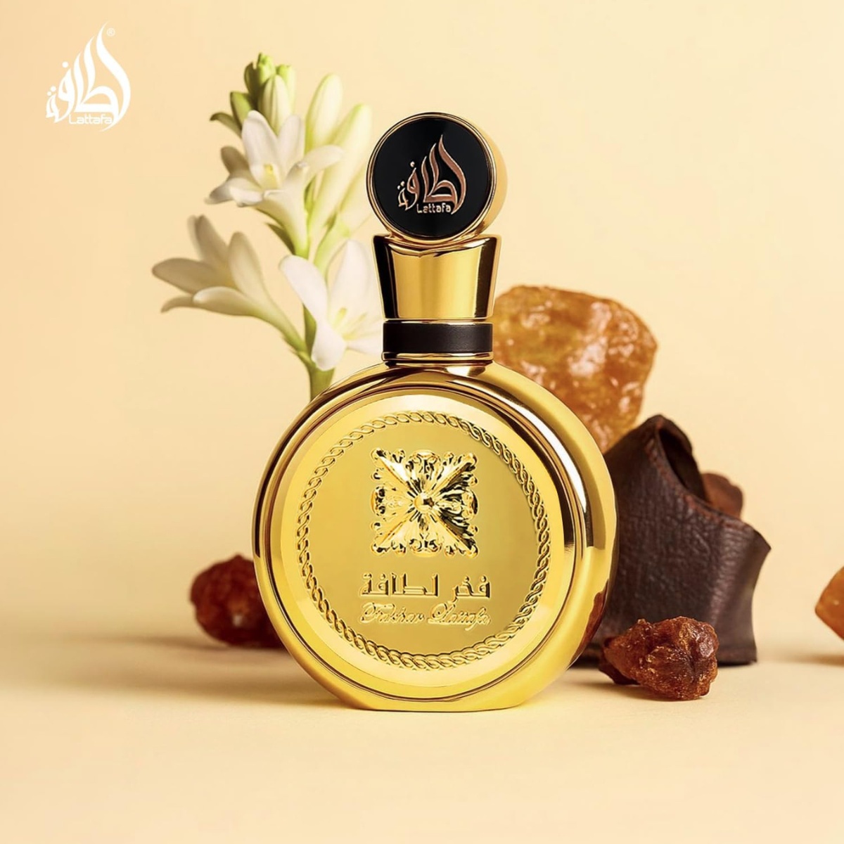 Frasco dourado de perfume árabe ao lado de resinas de âmbar e flores brancas